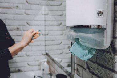 Coronavirus hijyeni. Tuvalette kağıt havlu ve alkol jeli antibakteriyel sabun dezenfektanı var. Kadın ellerini ve mendillerini kağıt havluyla yıkıyor.