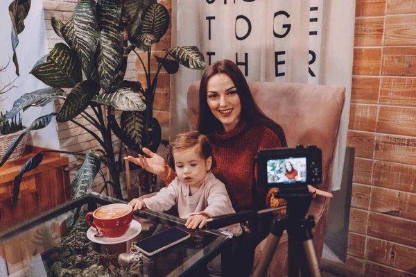 Online jobs for stay-at-home moms. Work From Home women with kids. Blogger girl and her little daughter have fun together. Young parenting blogger recording a video with her baby at home