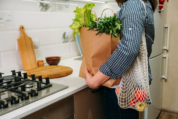 Farmers Cheap food delivery. Direct delivery from farms, buy local, support small food business. Woman unpacks shopping bag with fresh organic vegetable products in the kitchen at home