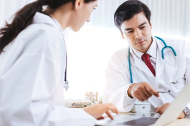 Doktor, doktorların ofisinde ya da hastane odasında dizüstü bilgisayar üzerinde çalışan bir ekiple çalışıyor. Kıdemli doktor tavsiyesi, klinikteki hastaları iyileştirmek ya da tedavi etmek için kıdemsiz doktora ders vermek. Hekimler uzmandır.