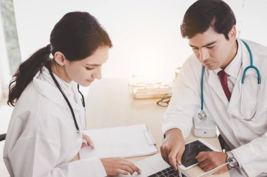 Doktorlar hastane odasında birlikte çalışıyorlar. Doktor kadın uzman doktoruna danışıyor ve adam dizüstü bilgisayarda ona tavsiye veriyor. Birkaç uzman doktor beyin fırtınası yapıyor, hasta davasını çözüyor.