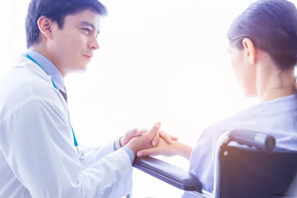 Doctor visit patient telling patient that she gets cancer. Doctor comforting, consoling, encourage by holding patients hand and ensuring would be safe. Patient get depressed, stress, sad on wheelchair