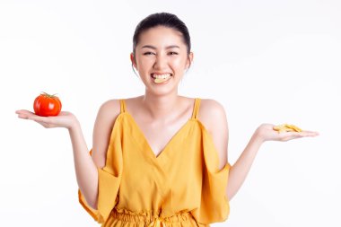Asyalı bir kadın seçiyor, atıştırıyor, patates cipsi yiyor, domates ve sebzeyi seçmiyor. Güzel genç bayan umursamaz, şişman olmaktan korkmaz çünkü zayıf kızın iyi bir diyet ve zayıflatma planı vardır. beyaz üzerine izole