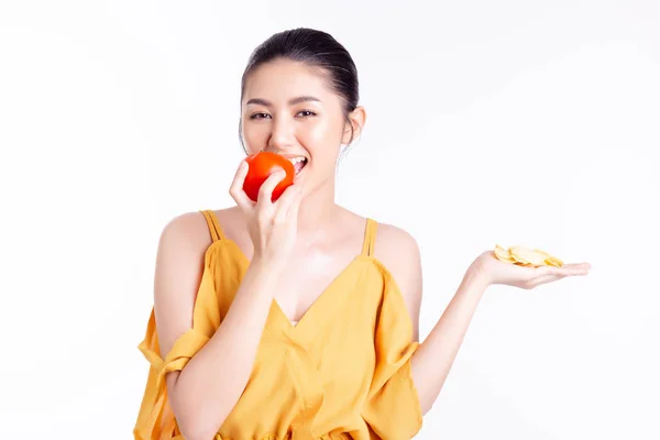 Ung asiatisk kvinna bantar genom att välja, äta grönsaker eller tomat som gör henne smal, smal och fin hud. Vacker ung asiatisk dam får god hälsa, bra utsöndringssystem efter äta hälsosam mat — Stockfoto