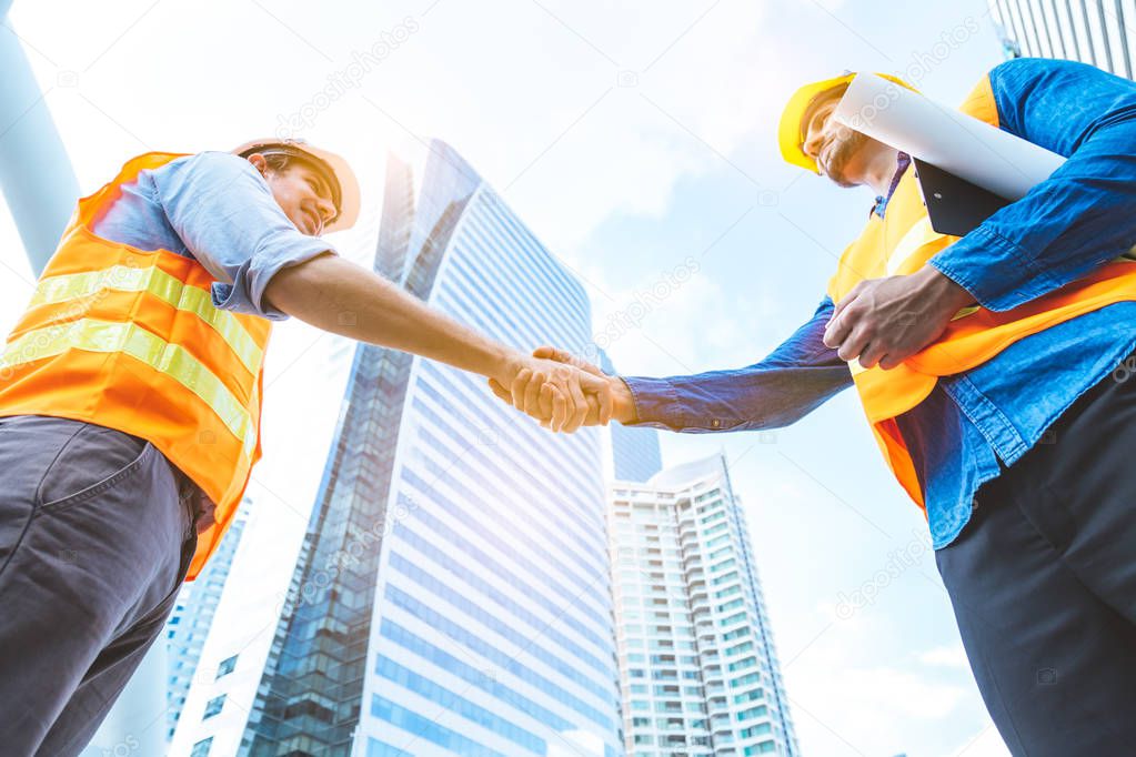 Engineer men making handshake in the city, high building background. Employee or worker shake hands to employer man for greeting, dealing, teamwork, collaboration project or business. successful team