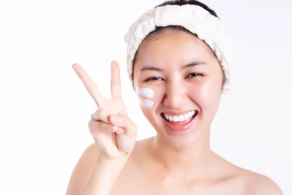 迷人的漂亮女人得了漂亮的面部皮肤 亚洲女人在洗完澡后在脸上涂上乳膏 乳液和美丽的皮肤 漂亮的亚洲姑娘用手指做V的标志来表示胜利 — 图库照片