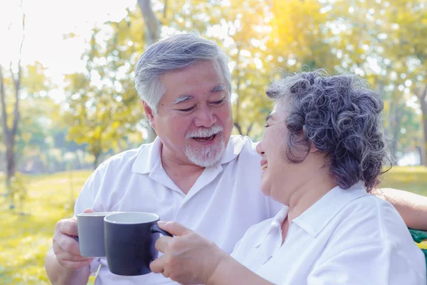 公園でおいしいホットコーヒーやお茶を飲んでいる老夫婦 年配の男女がコーヒーを飲みながら健康を祈願する 引退した夫婦が一緒に笑って — ストック写真