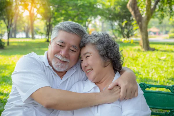 Romantic older couple. Elderly man or Senior asian husband embracing senior wife. Lovely elderly couple talking about their life, smiley faces at park. Old man and old woman love each other so much