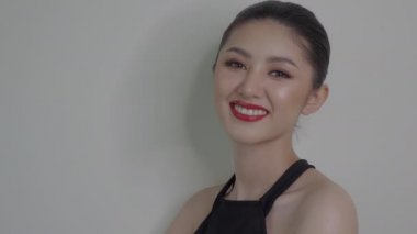 Güzel, genç Asyalı bir kadın, güzel, doğal bir makyajla gülümseyen yüzüyle onu mutlu ve kendinden emin yapar. Çekici genç Asyalı kız kırmızı dudaklar, güzel saç modeli, güzel elbise. 