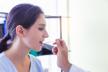 Doktor termometreyi hasta ateşini kontrol etmek için kullanıyor çünkü yabancı hasta ülkesine yeni döndü. Hastalanma riski var. Hasta hastalanır, ateşi yükselir, her yıl sağlığını kontrol eder.