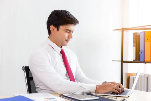 Young employee working on laptop computer during holiday in office at company. Businessman working on laptop computer for project. Smart guy need to work overtime to finish an order. work in workplace