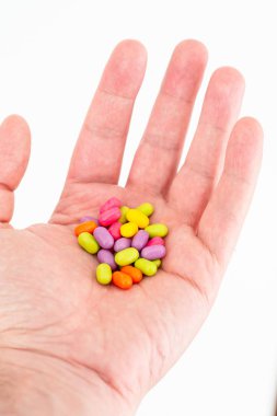 Caucasian male extended opened hand with colored small cylindric