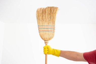 White Caucasian male hand with yellow latex glove holding a broo