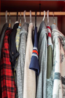 Dolap ahşap üzerinde çeşitli renkli kıyafetlerle dolu.