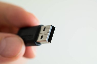 USB cable connector plug close up shot held between fingers by C
