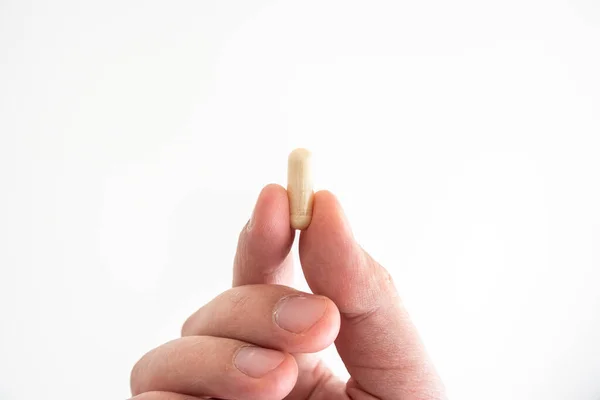Pastilla médica indescriptible sostenida entre los dedos por el hombre caucásico —  Fotos de Stock