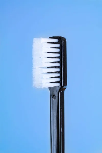 Simple new toothbrush with black plastic handle isolated on blue — 图库照片