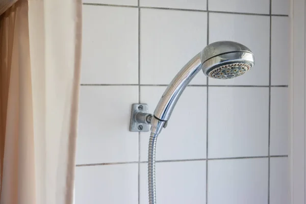 Kirli paslanmış kireçlenmiş kireçlenmiş kireçlenmiş duş başlığı kabinin içinde asılı duruyor. Görünür perde 2020.