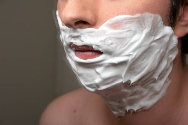 Banyo aynasında tıraş köpüğüyle kaplanmış beyaz erkek yüzü. 2020 model gözler yok.