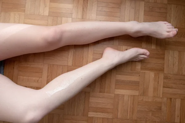 Caucasian young woman waxing her legs at home on the apartment floor no face unrecognizable 2020