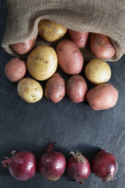 Batatas Vermelhas Douradas Saco Hessiano Com Cebolas Vermelhas Topo Mesa — Fotografia de Stock