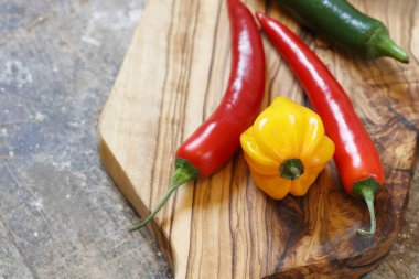 Kırmızı ve sarı sıcak biber kesme tahtası üzerinde kopya alanı sola ile eski ahşap masa üzerinde kapat