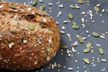 Rustik tam tahıl ekmek ekmek pişirme kayrak Taş Masa üstü ile dağınık tohum tepsi içinde yakın çekim