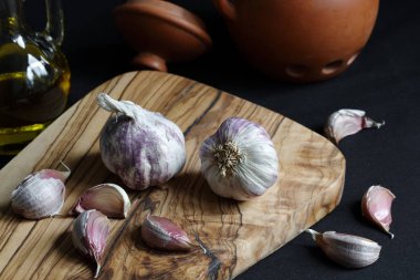 Işık gölge natürmort doğrama kurulu zeytinyağı ve kil konteyner üzerinde sarımsak ile