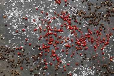 Kaya deniz tuzu ile kahverengi ve pembe peppercorns arduvaz arka plan üzerinde dağınık