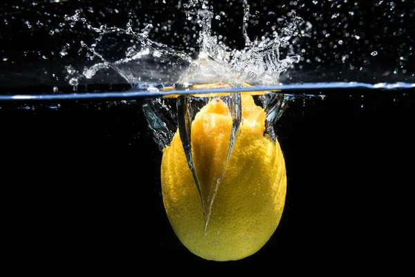 Citron tombant dans l'eau et éclaboussant gouttes sur backgr noir Images De Stock Libres De Droits