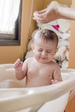 Renk banyo su dökerek başının üstünde bir bebek portresi.