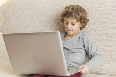 Çocuk kanepede oturup dizüstü bilgisayar izliyor..