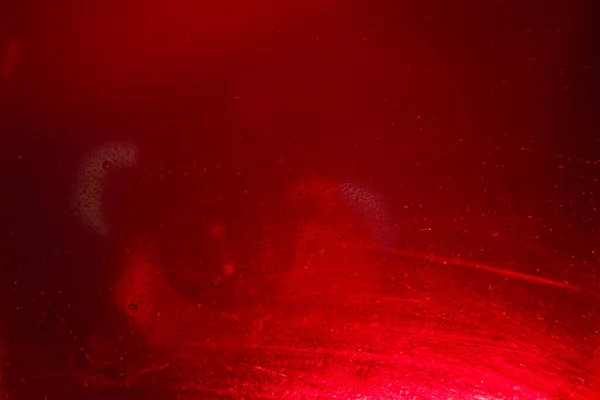 Glass with water drops on red background.