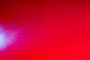 Glass with water drops on red background.