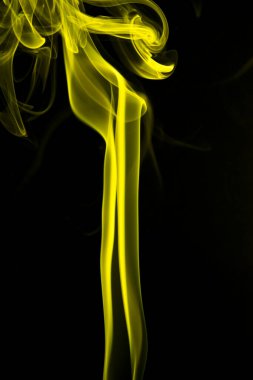 Siyah arkaplanda sarı dumanın soyut şekli.