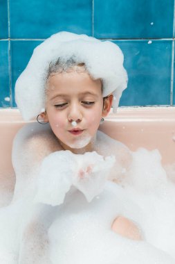 Küvette elinde köpükle dolaşan bir çocuğun portresi..