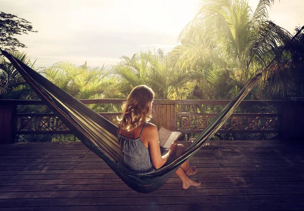 Mulher em um livro de leitura vestido em uma rede na selva em sóis — Fotografia de Stock