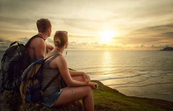 Pareja de excursionistas con mochilas disfrutando del amanecer en la cima de una montaña — Foto de Stock