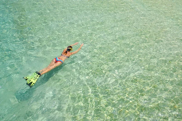 Mujer en traje de baño está nadando con snorkel y aletas en una wa azul —  Fotos de Stock