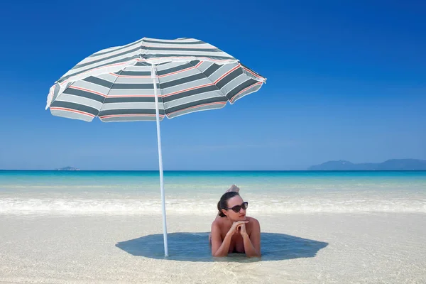 Mujer descansando bajo un paraguas de playa . —  Fotos de Stock