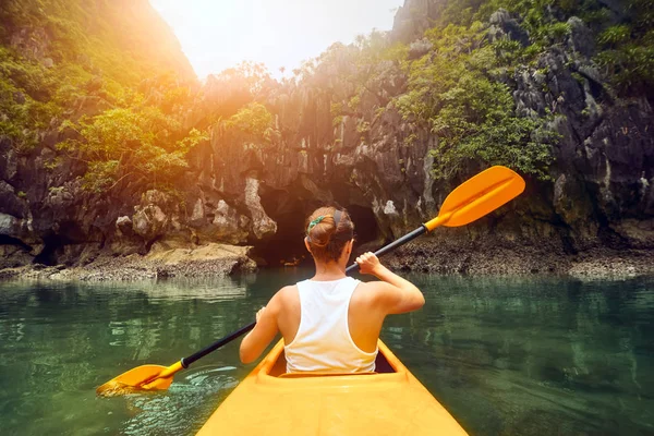 Purposeful woman paddling the kayak in the calm bay Halong among — Stock Photo, Image