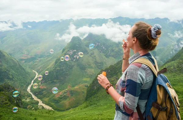 Мандрівник жінка дме мильні бульбашки в горах . — стокове фото