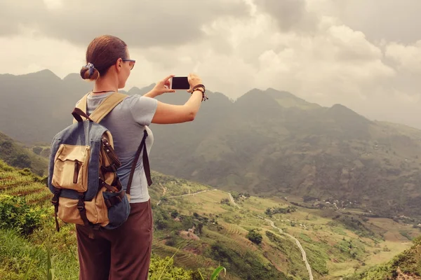 Молода жінка з рюкзаками подорожує і фотографує гори і — стокове фото