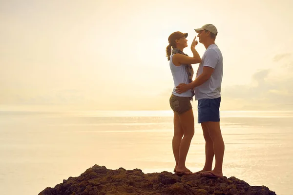 Jonge vrouw haar vriendje neus aanraken en glimlachen terwijl je op de top van de heuvel op zoek uitzicht op de zonsondergang in de Oceaan. — Stockfoto