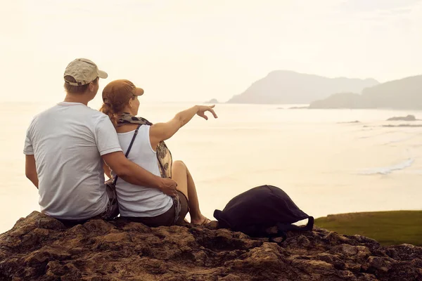 Pár turistů, sedí na kopci v plánu výlet do vzdálené ostrovy. — Stock fotografie