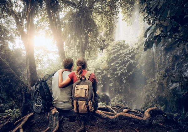 Pareja romántica excursionistas con mochilas disfrutando de la cascada vista en — Foto de Stock