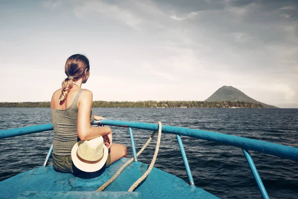 Wanita pelancong duduk di atas perahu mencari ke sebuah pulau — Stok Foto