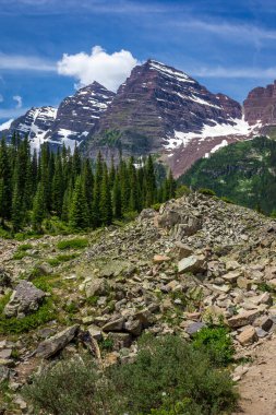 Güneşli bir günde, Colorado, Aspen yakınlarında mavi gökyüzü ile engebeli Krater Gölü patikasından görülen görkemli Maroon Bells tepeleri.