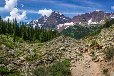 Güneşli bir günde, Colorado, Aspen yakınlarında mavi gökyüzü ile engebeli Krater Gölü patikasından görülen görkemli Maroon Bells tepeleri.