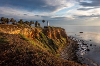 Gün batımında gökyüzünde renkli bulutlar ve sakin dalgaların kayalık kıyılara vurduğu Vicente Deniz fenerinin muhteşem uçurum manzarası, Rancho Palos Verdes, California
